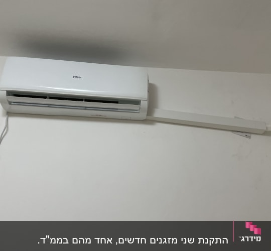 מזגן קיר לבן מותקן על קיר עם צינור חיבור